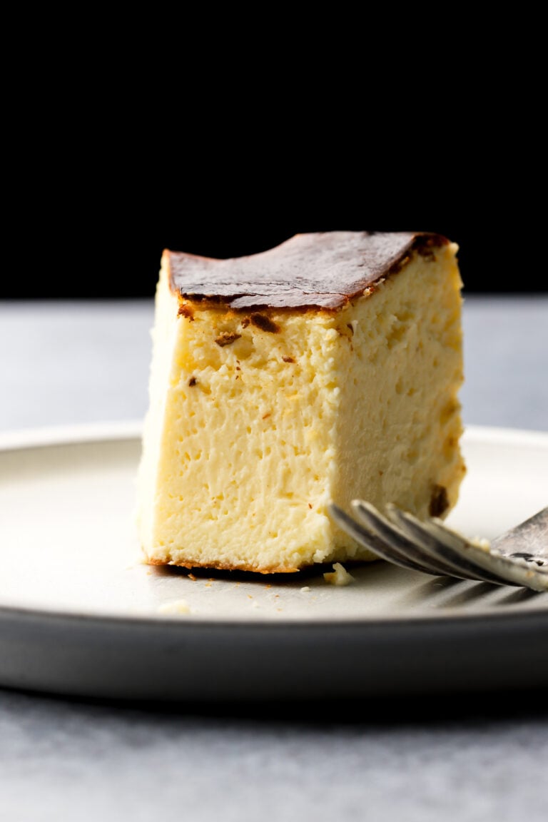 san sebastian cheesecake slice on a plate with a bite taken out