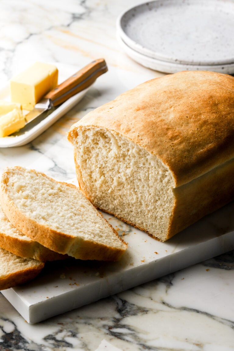 sandwich bread with two slices cut and butter in the background