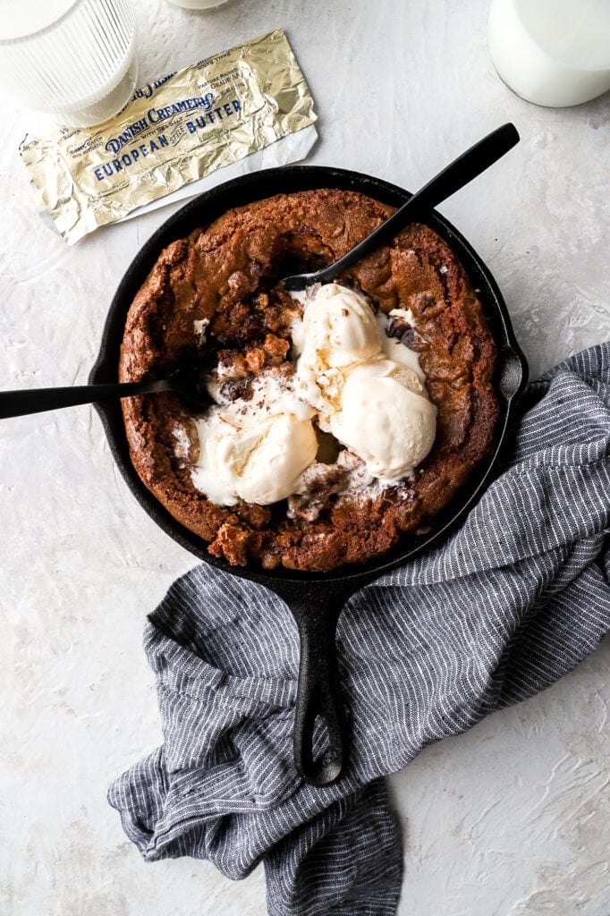 triple chocolate skillet cookie with ice cream, butter wrapper and spoons