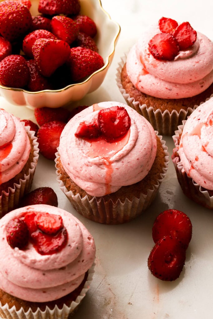 strawberry cupcakes with a bowl of strawberries
