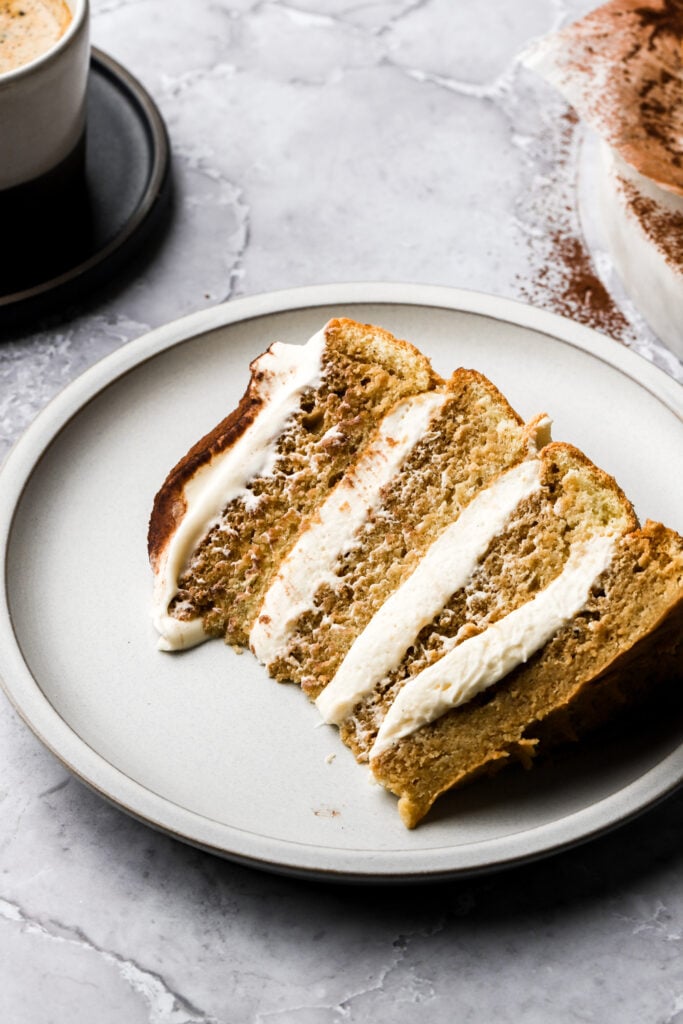 slice of cake on a plate with tea pot behind it