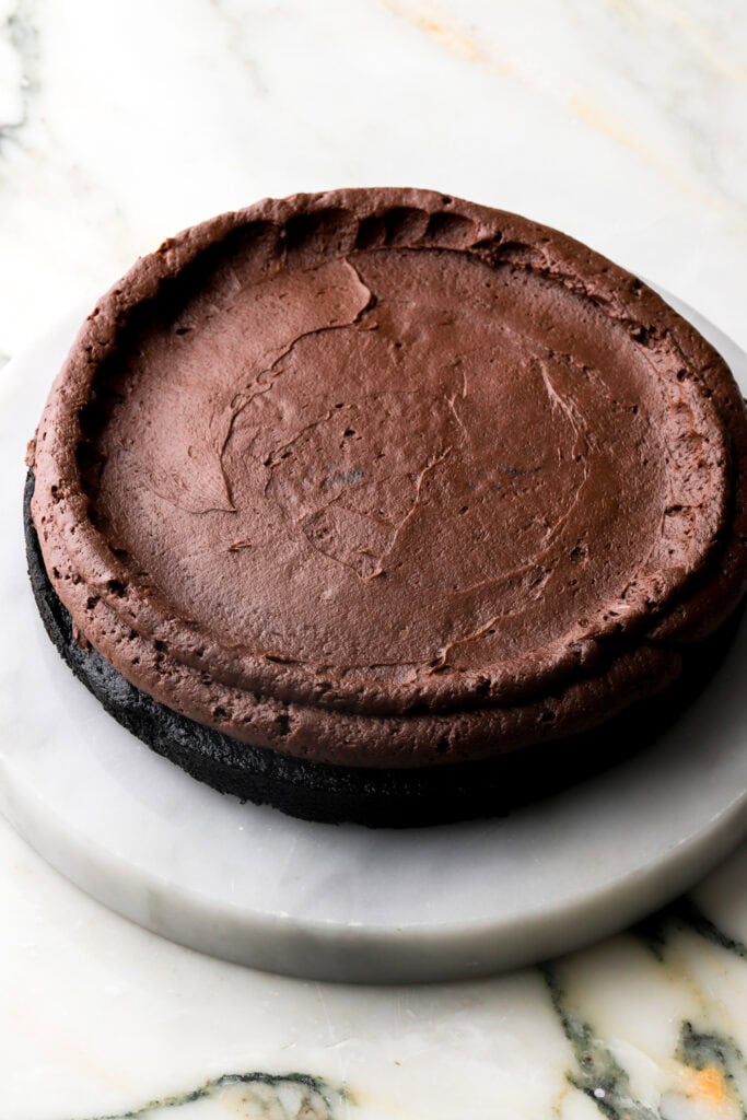 black cocoa cake with a layer of chocolate frosting and a border or frosting piped around the edge.