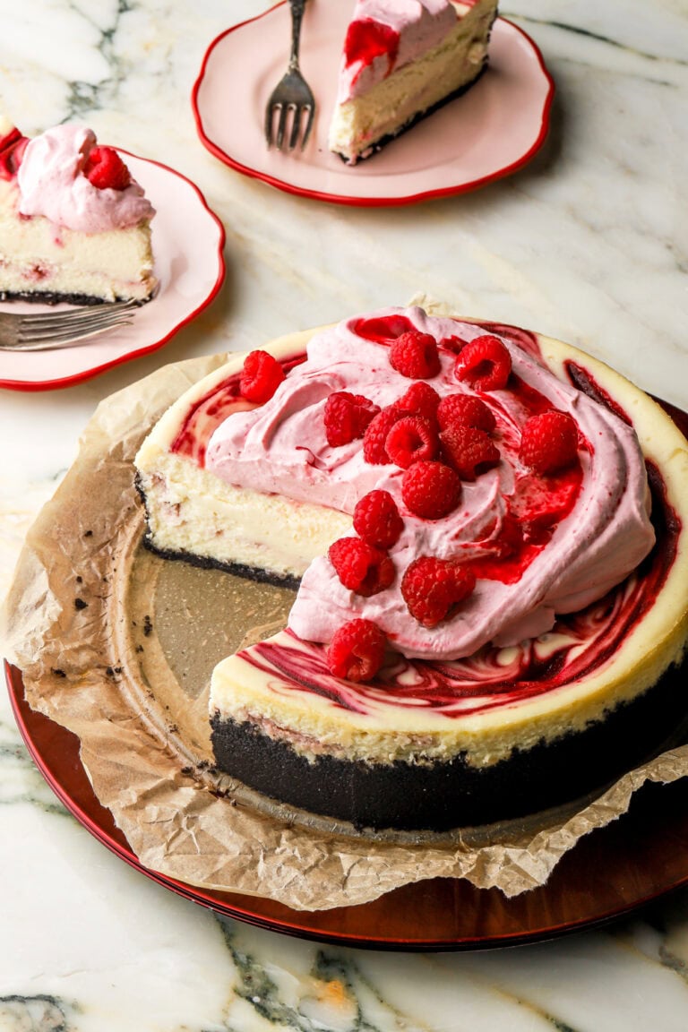inside of a white chocolate raspberry cheesecake with slices next to it