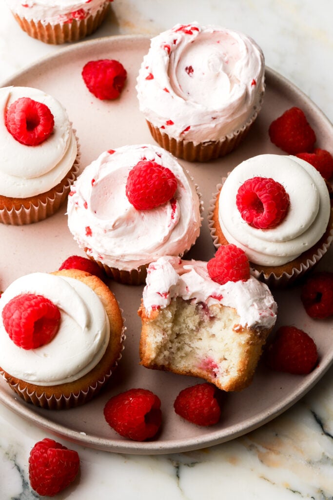 a bite taken out of a white chocolate raspberry cupcake