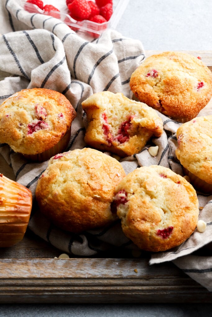 raspberry white chocolate muffins on a tray with a bite taken out